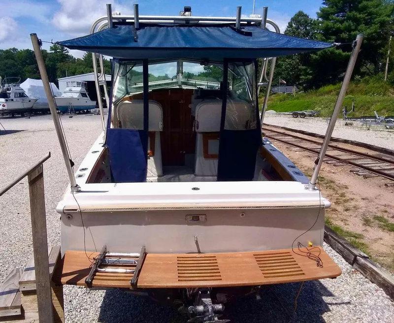Slide: The Image of 1987 Hinterhoeller Limestone Express boat with canopy, docked on gravel, rear view. - 5