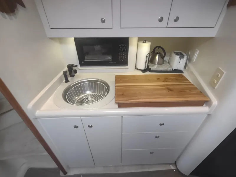 Slide: The Image of Compact kitchen area in 1998 Cruisers Yachts 3870 Esprit with sink, microwave, and cutting board. - 24