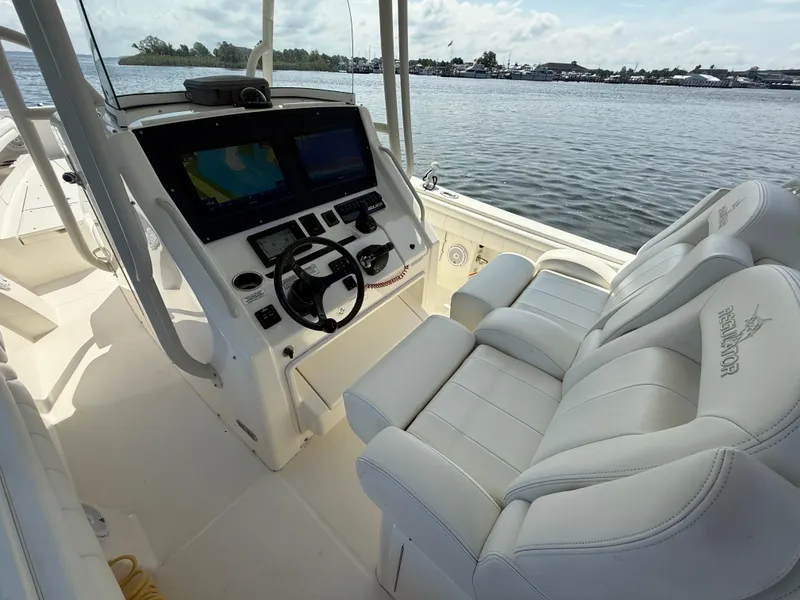 Slide: The Image of 2018 Regulator 31 boat interior with dual screens and plush seating, overlooking calm waters. - 20