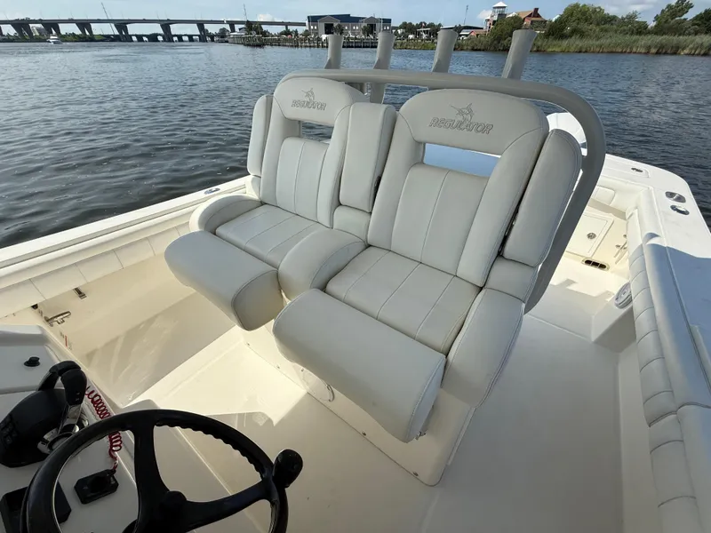 Slide: The Image of 2018 Regulator 31 boat with white cushioned seating, steering wheel, and water view. - 21