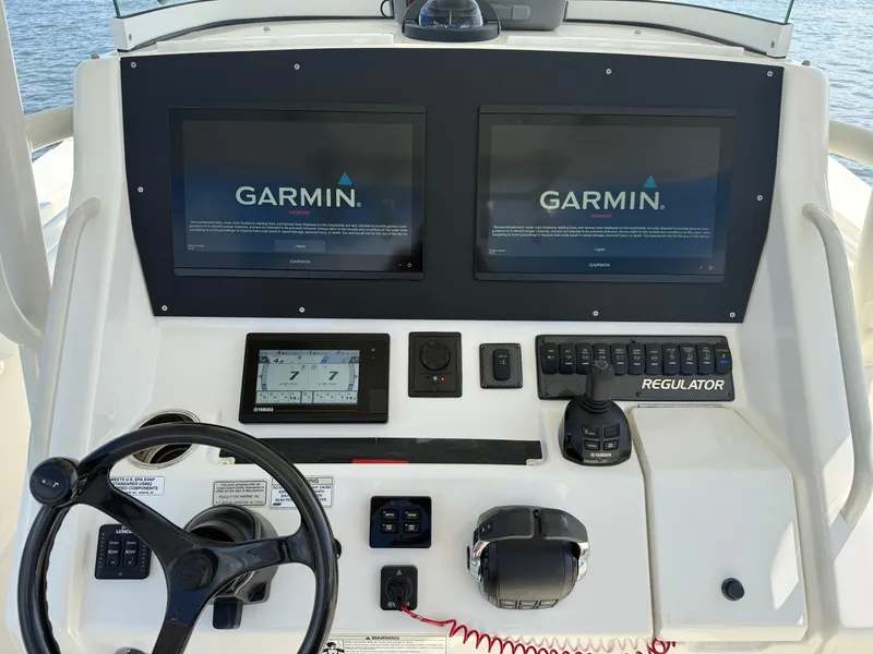 Slide: The Image of 2018 Regulator 31 boat dashboard with dual Garmin displays and steering controls. - 22