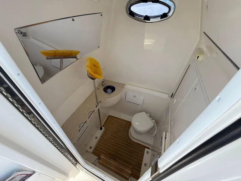 Slide: The Image of 2018 Regulator 31 boat bathroom with toilet, sink, mirror, and wooden floor. - 27