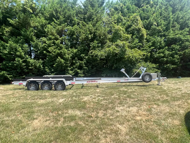 Slide: The Image of Triple-axle boat trailer on grass, surrounded by lush green trees. - 7