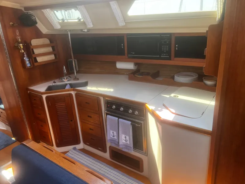 Slide: The Image of Interior of 1990 Catalina 42 sailboat kitchen with wood cabinetry and modern appliances. - 24
