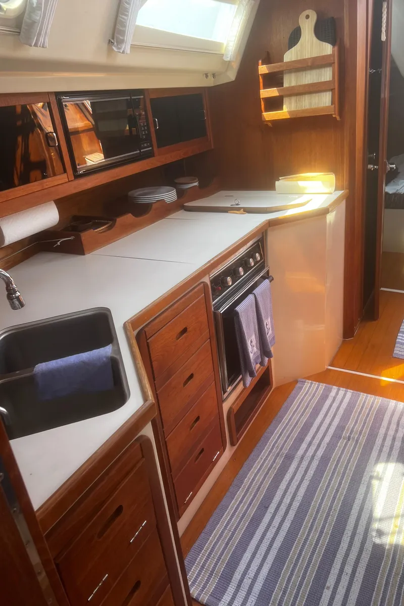 Slide: The Image of Catalina 42 yacht kitchen interior, 1990 model, featuring wooden cabinetry and modern appliances. - 25