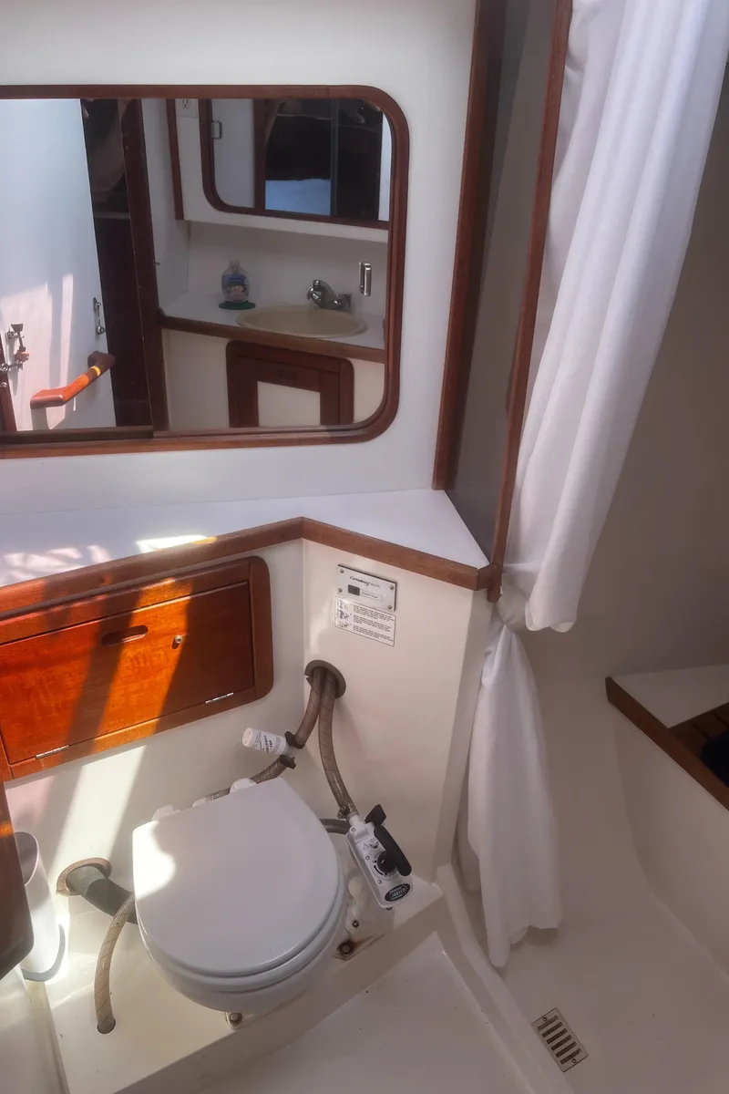 Slide: The Image of 1990 Catalina 42 yacht bathroom with toilet, mirror, and wooden accents. - 34