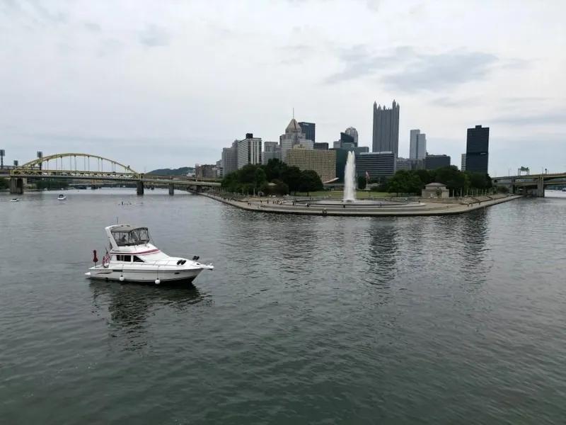 Slide: The Image of 1999 Silverton 37 Convertible boat on river with city skyline and fountain. - 11