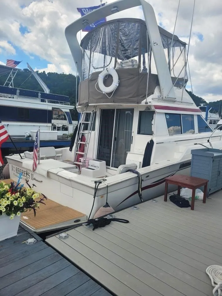 Slide: The Image of 1999 Silverton 37 Convertible yacht docked at marina with American flags. - 26