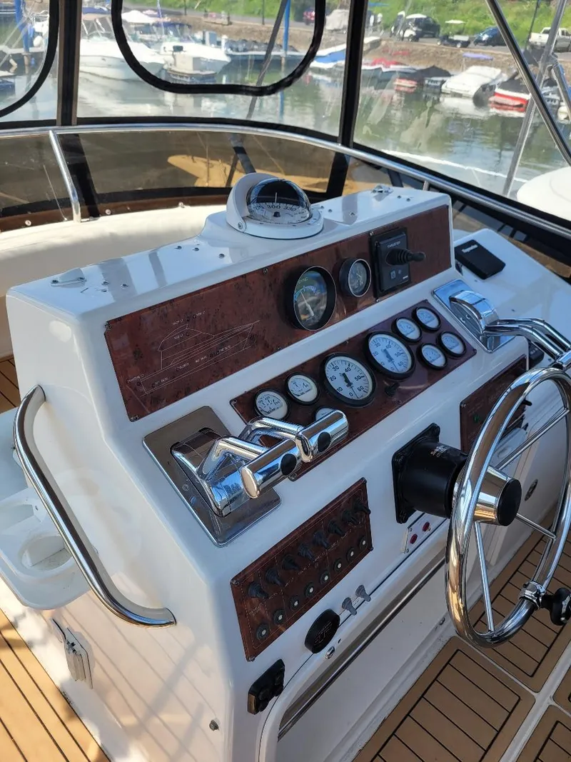 Slide: The Image of 1999 Silverton 37 Convertible helm with gauges and controls, docked at marina. - 41