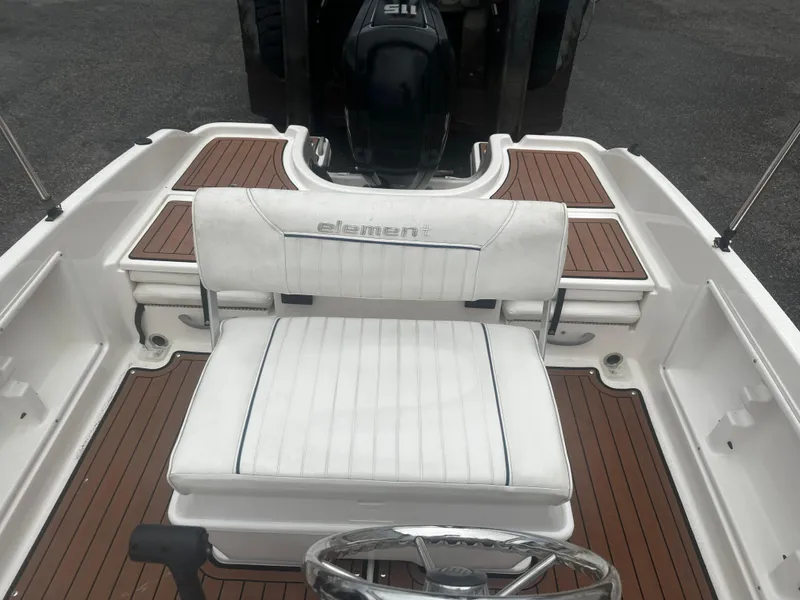 Slide: The Image of 2017 Bayliner Element F18 boat interior with white seating and wood accents. - 21