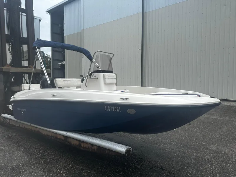 Slide: The Image of 2017 Bayliner Element F18 boat with blue hull, docked near a warehouse. - 4