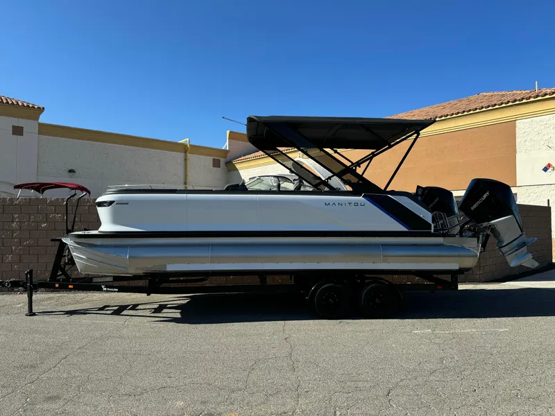 The Image of 2025 Manitou Explore 24 Switchback pontoon boat with trifold bench, parked on trailer. - 1