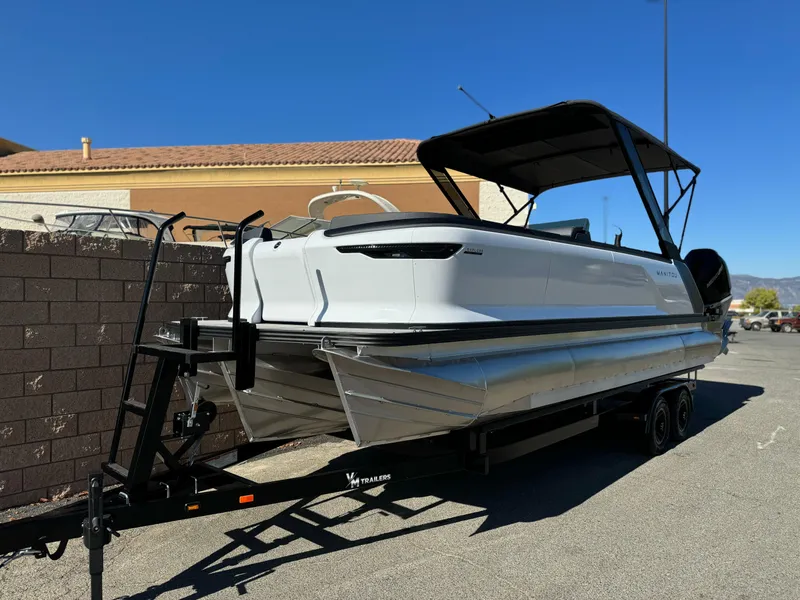 Slide: The Image of 2025 Manitou Explore 24 Switchback boat on trailer, featuring trifold bench and dual SHP. - 2