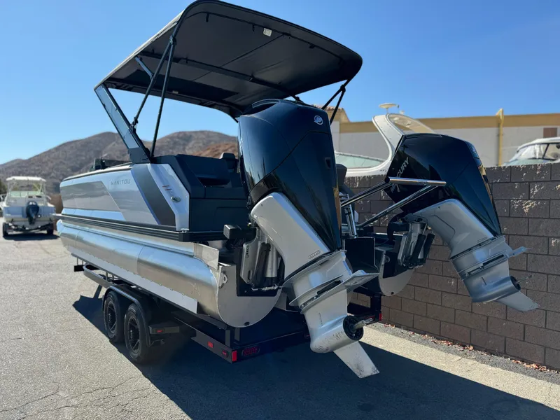 Slide: The Image of 2025 Manitou Explore 24 Switchback boat with dual engines and trifold bench on trailer. - 4