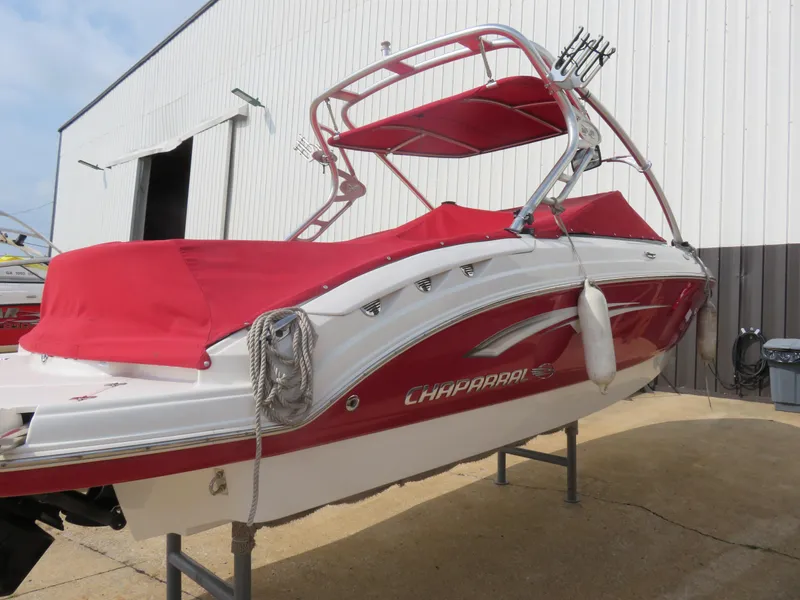 Slide: The Image of 2008 Chaparral SSX 236 boat with red cover, docked outside a warehouse. - 2