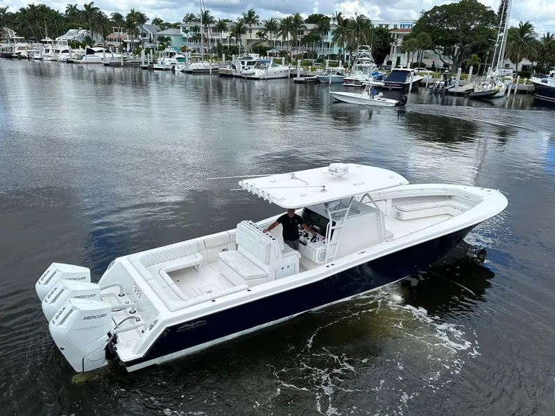 Slide: The Image of 2013 Invincible 42 Open Fisherman boat on calm water, featuring triple outboard engines. - 9