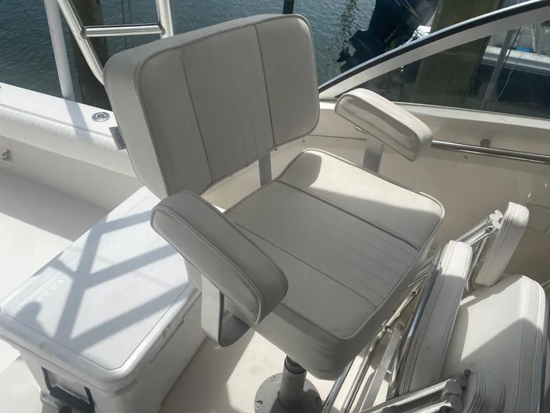 Slide: The Image of Albemarle 280 Express Fisherman 2000 boat seat with armrests, white upholstery, and cooler nearby. - 16