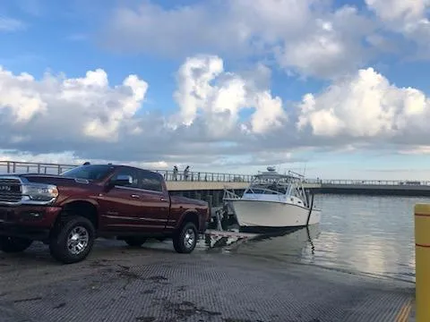 Slide: The Image of Truck towing 2000 Albemarle 280 Express Fisherman boat at a boat ramp under cloudy sky. - 2