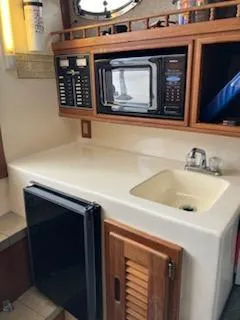 Slide: The Image of 2000 Albemarle 280 Express Fisherman galley with microwave, sink, and mini fridge. - 39