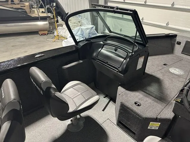 Slide: The Image of 2025 Lund 2075 Fisherman Sport interior with seating and dashboard in a garage setting. - 12