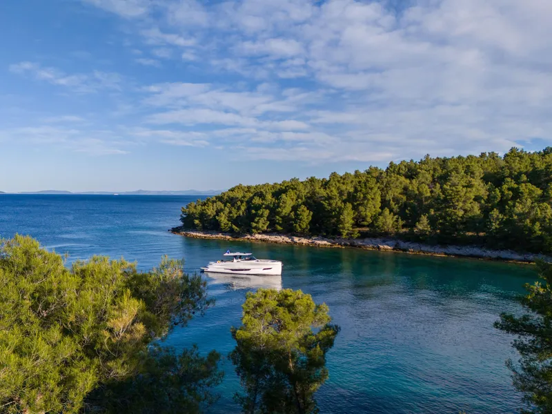 Slide: The Image of Solaris Power 60 Open yacht in serene coastal waters, surrounded by lush greenery, 2025 model. - 23