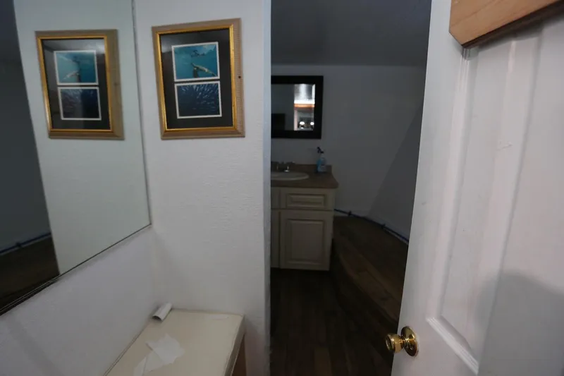 Slide: The Image of Interior of 1988 Winston Knauss 64 boat, featuring a bathroom with framed pictures and a mirror. - 22