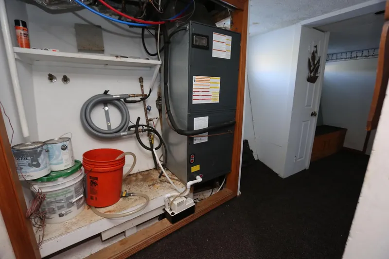 Slide: The Image of Utility area on 1988 Winston Knauss 64 Party Boat with HVAC system and storage items. - 26