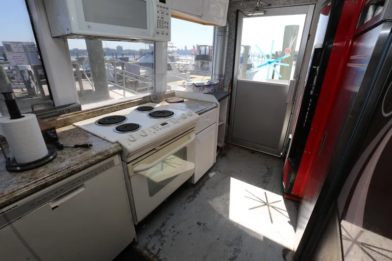 Slide: The Image of Kitchen area on 1988 Winston Knauss 64 party boat with stove, microwave, and outdoor view. - 28