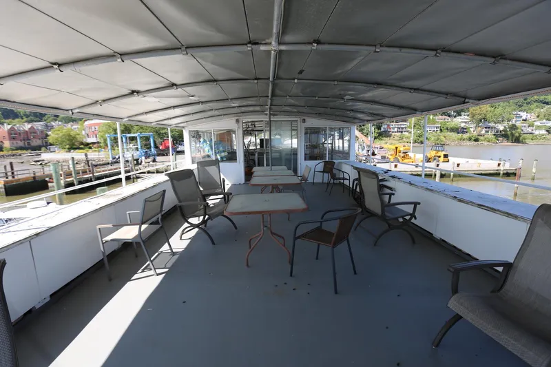 Slide: The Image of 1988 Winston Knauss 64 party boat deck with chairs and tables, docked at a scenic harbor. - 39