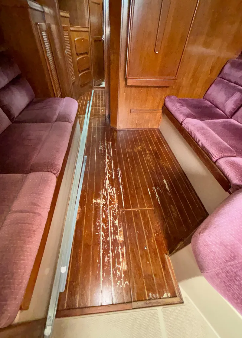 Slide: The Image of Interior of 1987 Island Packet 38 sailboat with wooden flooring and purple seating. - 10