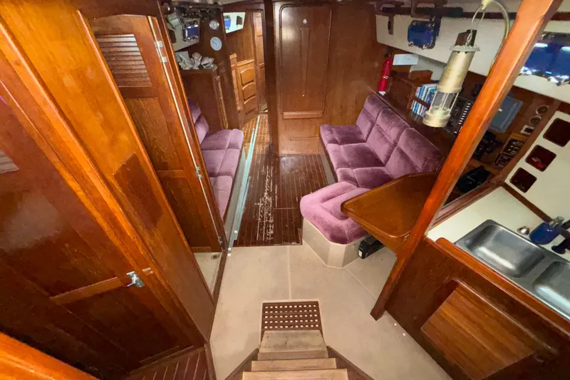 Slide: The Image of Interior of 1987 Island Packet 38 sailboat with wood finish and purple seating. - 2