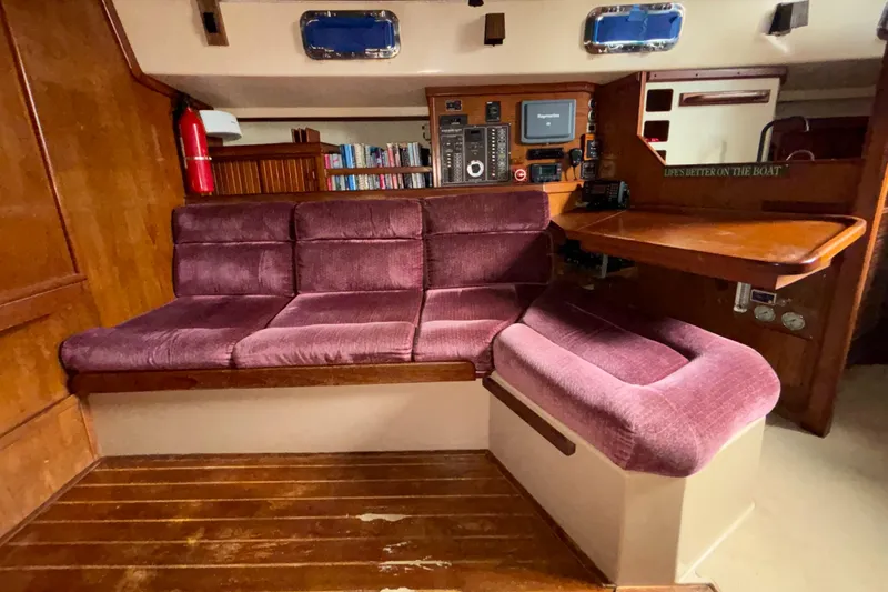 Slide: The Image of Interior of 1987 Island Packet 38 sailboat with purple seating and wooden accents. - 22