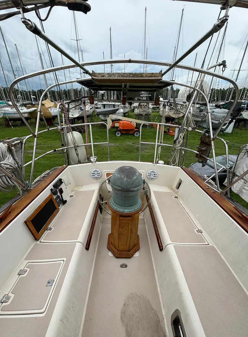 Slide: The Image of 1987 Island Packet 38 sailboat cockpit with steering wheel and marina background. - 31