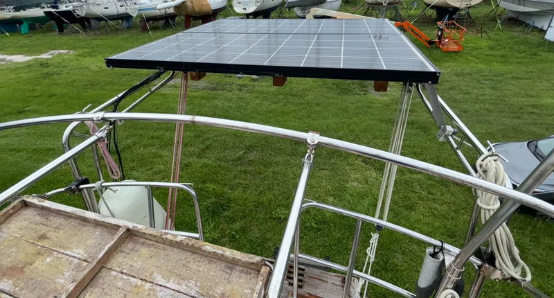 Slide: The Image of 1987 Island Packet 38 sailboat with solar panel installation on deck, surrounded by grass and other boats. - 32