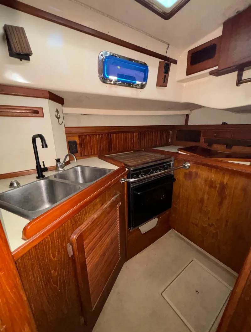 Slide: The Image of 1987 Island Packet 38 sailboat kitchen with wood cabinetry, double sink, and stove. - 4