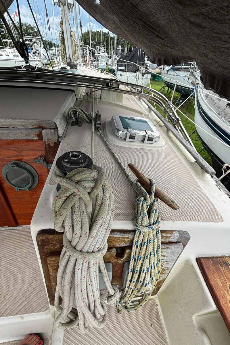 Slide: The Image of 1987 Island Packet 38 sailboat deck with ropes and winch in marina setting. - 43