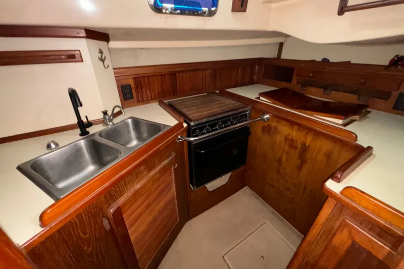 Slide: The Image of 1987 Island Packet 38 yacht kitchen with wood cabinetry, double sink, and stove. - 5