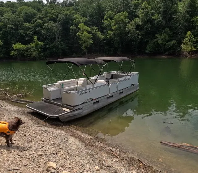 Slide: The Image of 1988 Sun Tracker PARTY BARGE pontoon boat docked by a forested lake shore. - 14