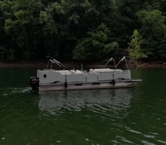Slide: The Image of 1988 Sun Tracker PARTY BARGE pontoon boat on a serene lake with forest backdrop. - 16
