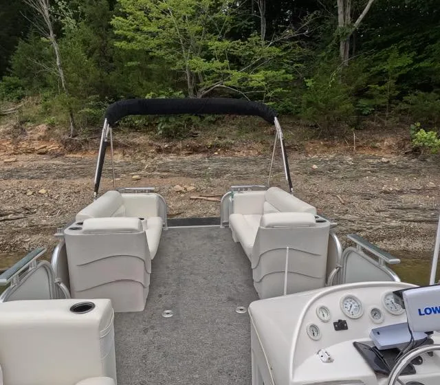 Slide: The Image of 1988 Sun Tracker PARTY BARGE pontoon boat with seating, docked by a wooded shoreline. - 23