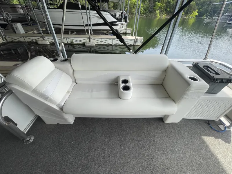 Slide: The Image of 1988 Sun Tracker PARTY BARGE white seating with cup holders, docked by a serene lake. - 26