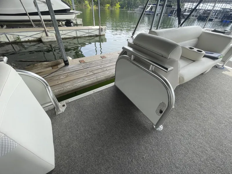 Slide: The Image of 1988 Sun Tracker PARTY BARGE interior with gray carpet and white seating at a dock. - 30