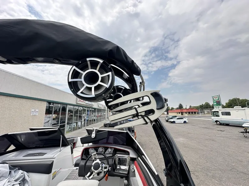 Slide: The Image of 2014 Tigé ASR boat with speakers and wakeboard rack, parked near a store. - 31