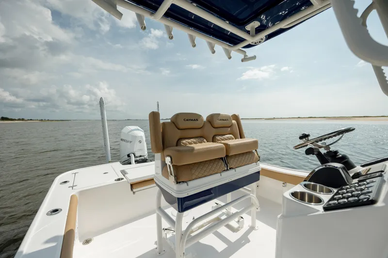 Slide: The Image of 2025 Caymas 26 HB boat interior with helm and seating, on calm water. - 13