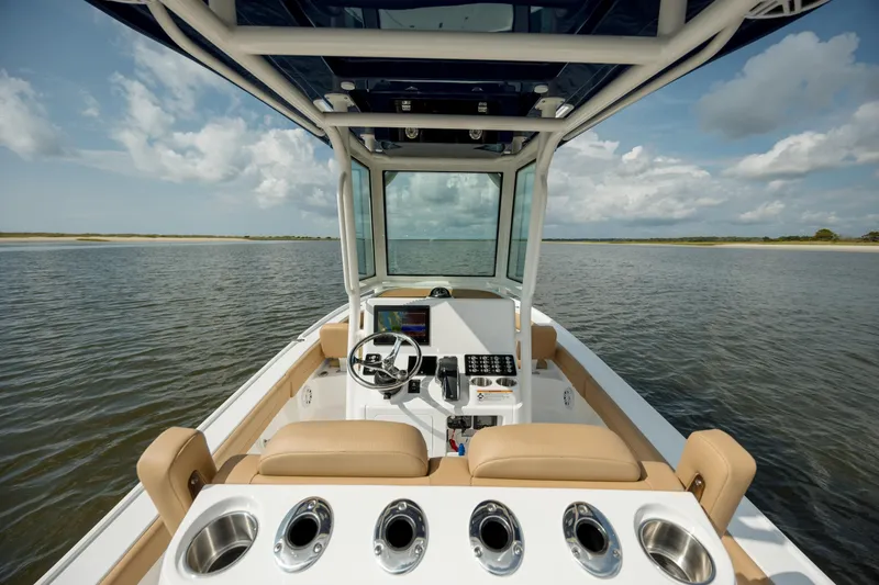 Slide: The Image of 2025 Caymas 26 HB boat interior with helm, seating, and cup holders on calm water. - 16