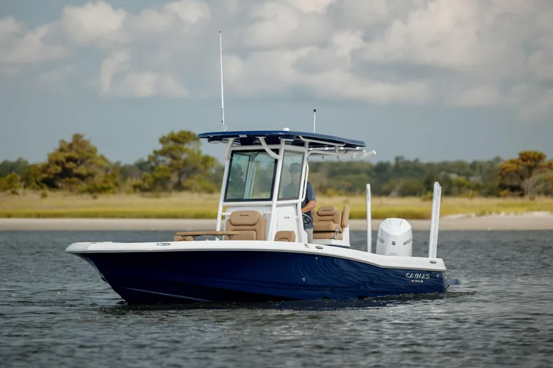 Slide: The Image of 2025 Caymas 26 HB boat on calm water with scenic background. - 6