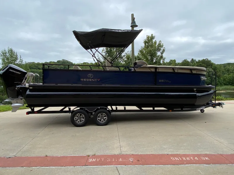 The Image of 2024 Regency 250 DL3 pontoon boat on trailer, parked outdoors. - 0