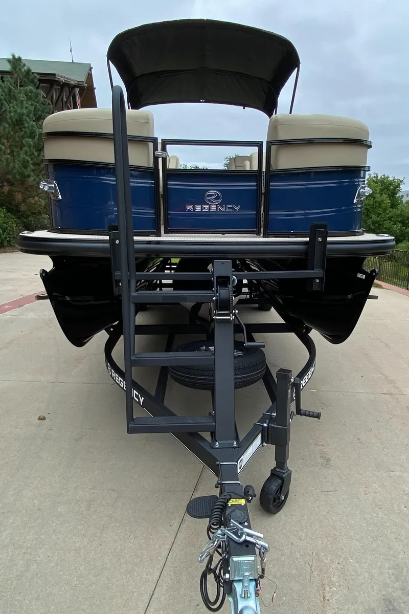 Slide: The Image of 2024 Regency 250 DL3 pontoon boat on trailer, front view. - 2