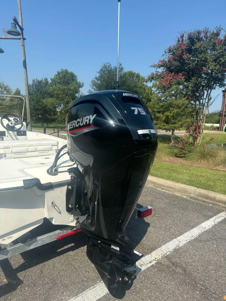 Slide: The Image of 2024 Mako Pro Skiff 17 CC with Mercury 75 outboard motor in a parking lot. - 1