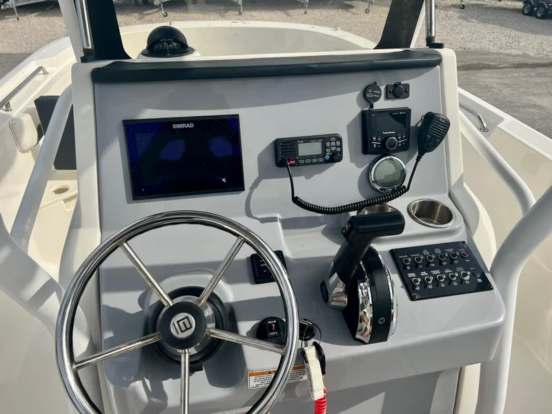 Slide: The Image of 2023 Trophy T24CC boat dashboard with steering wheel and navigation controls. - 13